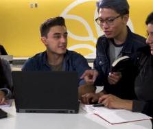 四个学生坐在一台笔记本电脑前